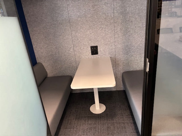 Large paxton workpod meeting room with a table and sofas against a gray wall.