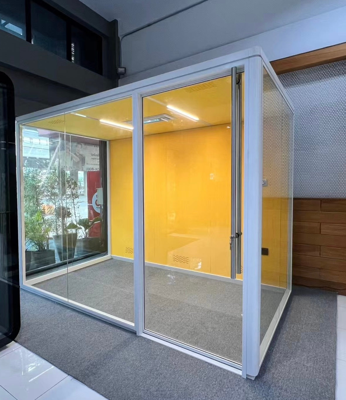 Modern small cube office pod with glass walls and yellow interior