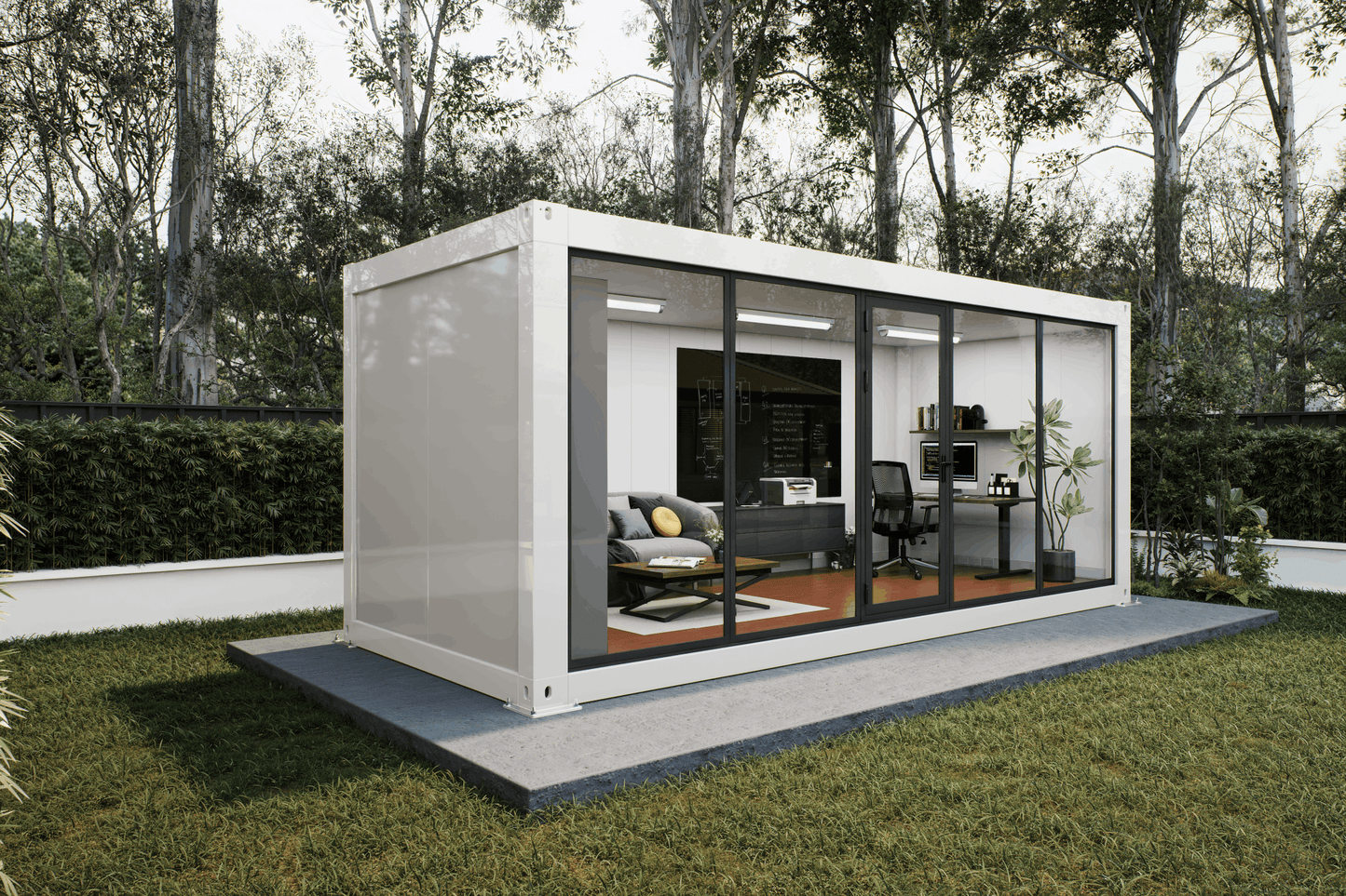 A modern white shipping container home with large glass sliding doors, shown on a concrete platform in a grassy backyard with trees in the background. The interior is furnished with a gray sofa, office desk, and chair.
