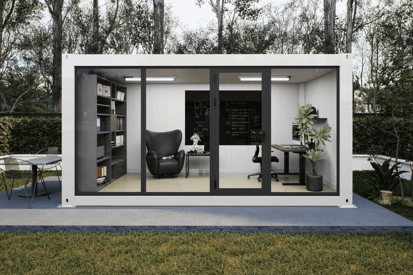 A modern white modular office pod with large black-framed glass sliding doors, shown on a concrete patio in a grassy backyard with trees. The interior features a black leather armchair, a desk with a computer, shelving, and plants.
