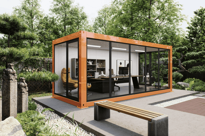 A modern modular office pod with an orange-brown metal frame and large glass windows, shown in a landscaped garden setting with a bench in the foreground.